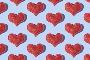 Muster aus glitzernder Herzform auf farbigem Hintergrund mit hartem Schatten. Valentinstag minimalistisches Design foto