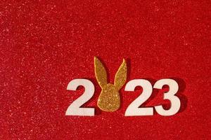 Holzzahlen 2023 mit Hasenohren symbolisieren das neue Jahr auf farbigem Hintergrund foto