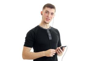 charmanter junger typ in einem t-shirt hört musik mit kopfhörern foto