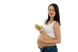 schöne junge Brünette schwangere Mädchen mit grünen Äpfeln in ihren Händen posiert isoliert auf weißem Hintergrund foto