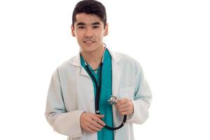 glücklicher junger männlicher Arzt in Uniform mit Stathoskop posiert isoliert auf weißem Hintergrund foto