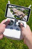 Hände halten Drohnen-Quadcopter-Controller mit Wohnhäusern auf dem Bildschirm foto