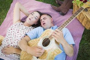 Mischlingspaar im Park, das Gitarre spielt und singt foto