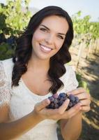 junge erwachsene Frau, die die Weintrauben im Weinberg genießt foto