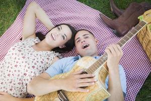 Mischlingspaar im Park, das Gitarre spielt und singt foto