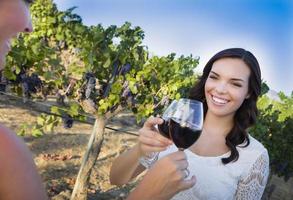 junge frau, die mit freunden ein glas wein im weinberg genießt foto