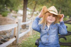 süßes junges mädchen mit cowboyhut, das draußen für ein porträt posiert foto