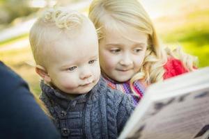 Mutter, die ihren beiden entzückenden blonden Kindern ein Buch vorliest foto