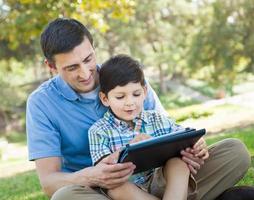 glücklicher vater und sohn, die draußen auf einem computertablett spielen. foto