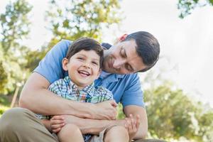 liebevoller junger Vater, der Sohn im Park kitzelt. foto