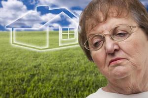 melancholische Seniorin mit Rasenfläche und Geisterhaus dahinter foto