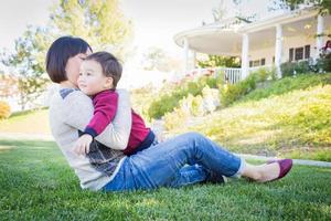 glückliche chinesische mutter, die spaß mit ihrem gemischtrassigen babysohn im freien hat foto