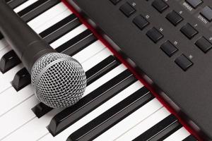 Mikrofon, das auf elektronischer Synthesizer-Tastaturzusammenfassung liegt foto