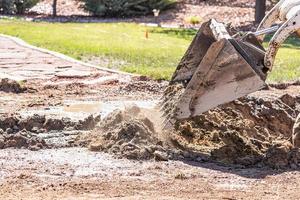 kleiner Bulldozer, der im Hof für die Poolinstallation gräbt foto