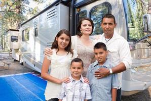 Glückliche hispanische Familie vor ihrem schönen Wohnmobil auf dem Campingplatz. foto