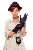 Rothaarige Detektivin zieht Handschuhe an und trägt einen Trenchcoat foto