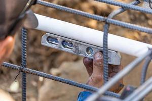 Klempner mit Wasserwaage bei der Installation von PVC-Rohren auf der Baustelle foto