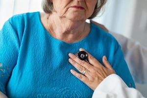 Ärztin, die das Herz mit Stethoskop einer älteren erwachsenen Frau überprüft foto