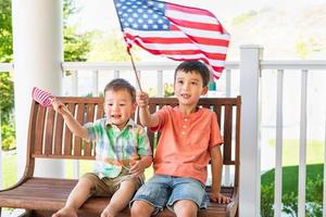 junge gemischtrassige chinesische und kaukasische brüder, die mit amerikanischen flaggen spielen foto