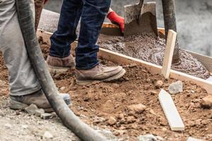 Bauarbeiter gießen und nivellieren nassen Zement in Holzrahmen foto