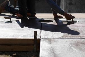 Bauarbeiter, der nassen Zement mit Kellenwerkzeugen glättet foto