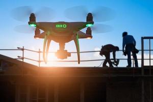 Silhouette einer unbemannten Quadrocopter-Drohne in der Luft auf der Baustelle foto