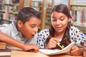 hispanischer Junge und Mädchen haben Spaß beim gemeinsamen Lernen in der Bibliothek foto