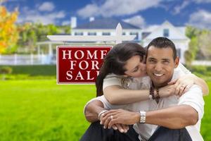hispanisches Paar, neues Zuhause und zu verkaufendes Immobilienschild foto