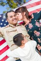 männlicher hispanischer Soldat der Streitkräfte, der seine Rückkehr mit amerikanischer Flagge feiert foto