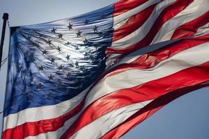 hintergrundbeleuchtete amerikanische flagge, die im wind gegen einen tiefblauen himmel weht foto