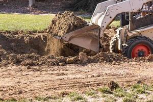 kleiner Bulldozer, der im Hof für die Poolinstallation gräbt foto