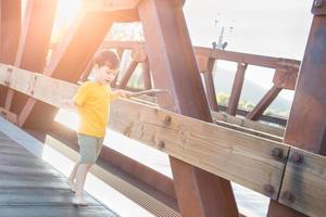 Chinesischer und kaukasischer Junge der gemischten Rasse, der allein auf Brücke spielt foto