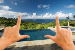 Hände, die den Pool und die Terrasse mit Meerblick einrahmen foto