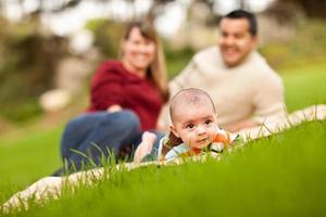 glücklicher kleiner Junge und Eltern gemischter Rassen, die im Park spielen foto