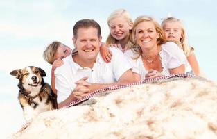 glückliches kaukasisches familien- und hundeporträt am strand foto