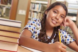 hispanische Studentin, die in der Bibliothek studiert foto