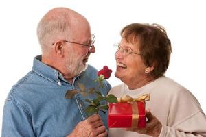 glückliches älteres paar mit geschenk und roter rose foto