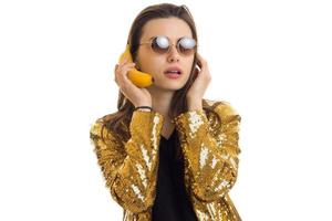 junge stilvolle frau in goldener jacke mit banan foto