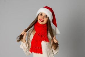 Mädchen in Weihnachtsmütze und rotem Schal foto