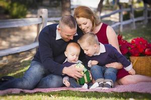 kleine junge familie, die weihnachtsgeschenke im park öffnet foto