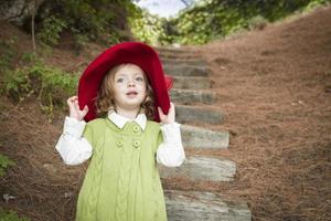 entzückendes Kindermädchen mit rotem Hut, das draußen spielt foto