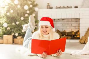 weihnachts-, komfort-, freizeit- und menschenkonzept - nahaufnahme einer glücklichen jungen frau, die zu hause über schnee ein buch liest foto