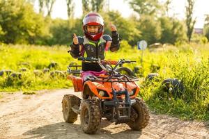 kleines mädchen, das atv quad bike auf der rennstrecke fährt foto