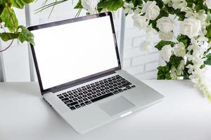 Laptop mit leerem Bildschirm, schöne Rosen und Eukalyptusblumenstrauß, weißer Vintage-Pastellhintergrund. Blog-, Website- oder Social-Media-Konzept foto