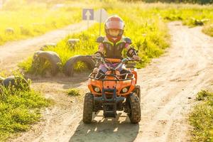 kleines mädchen, das atv quad bike auf der rennstrecke fährt foto