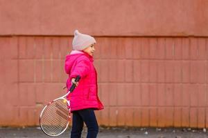 Porträt eines süßen kleinen Mädchens, das Tennis spielt. foto