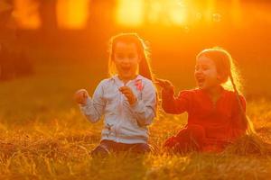 Zwei kleine Mädchen blasen Seifenblasen, Outdoor-Shooting foto