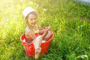 kleines Mädchen sitzt im Becken mit Wasser. heißer Sommertag foto