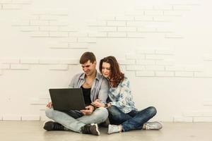 Paar beim Online-Shopping am Laptop-Computer - zwei junge Freunde, die sich im Wohnzimmer ein Video auf einem Notebook ansehen foto