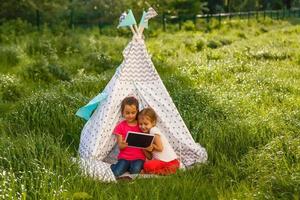 Zwei kleine Mädchen spielen in der Nähe des Wigwam-Zeltes foto